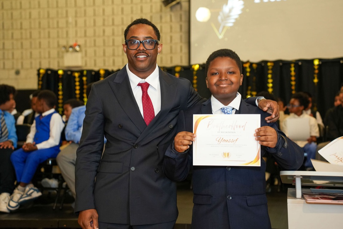 A young man with his certificate beside the founder.