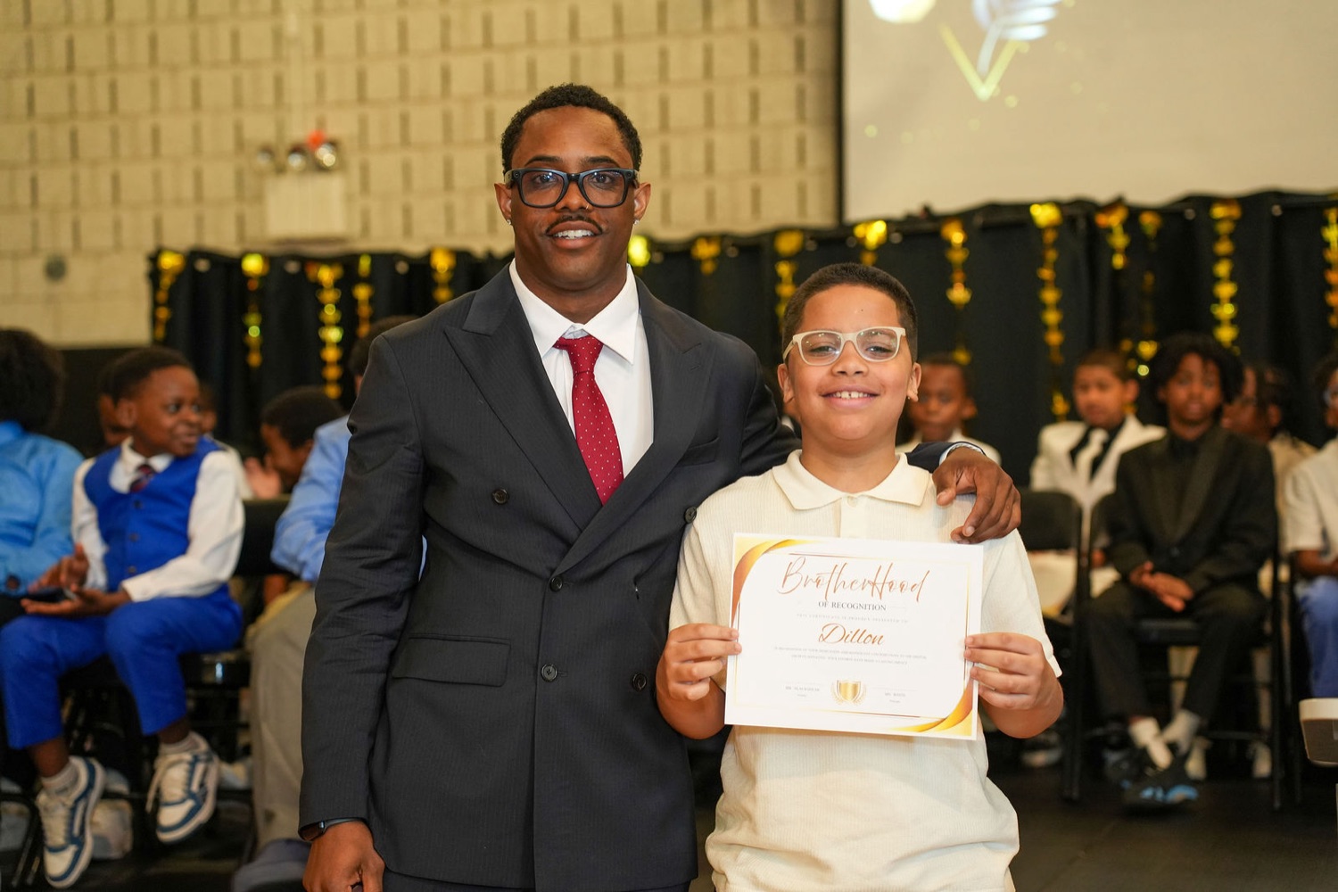 A mentor and a young man on stage during the Brotherhood induction.