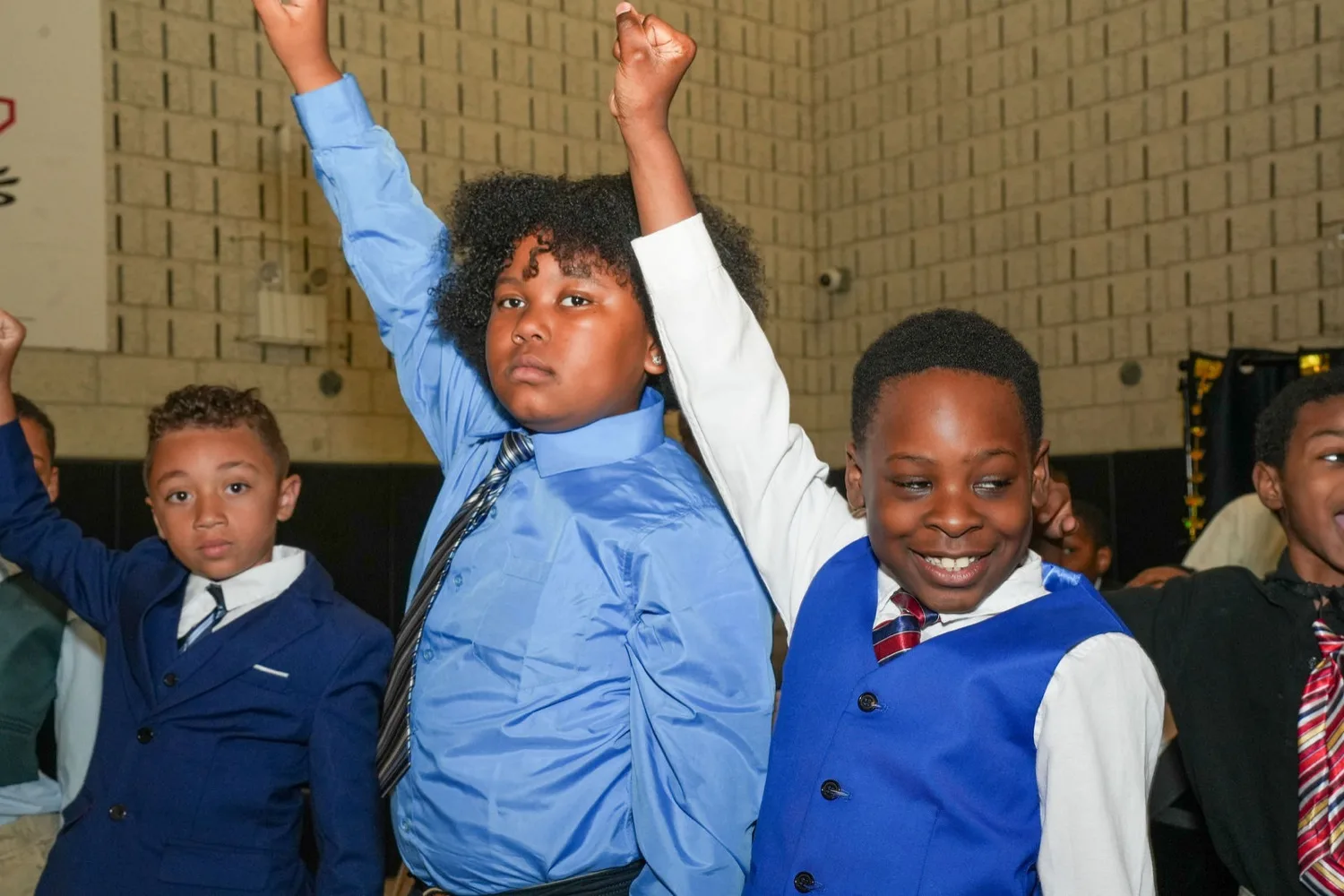 Young men celebrating with raised fists at the Brotherhood induction.